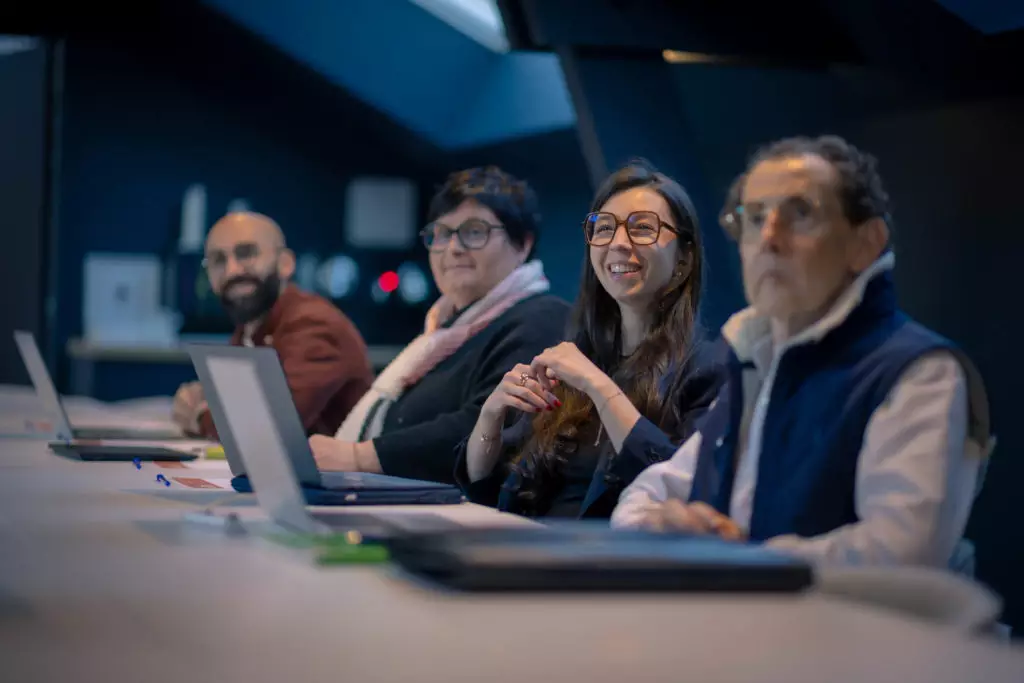 Quatre personnes souriantes avec ordinateurs assistent à un atelier culinaire chez Salt & Pepper Dijon en entreprise.