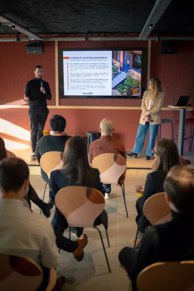 Intervenant présentant un atelier culinaire team building devant participants, écran affichant slides de cuisine.