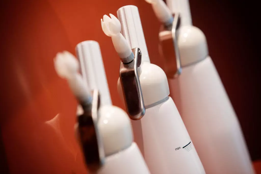 Trois brosses à dents électriques blanches alignées sur fond rouge, avant-plan net, pour atelier culinaire d'entreprise.