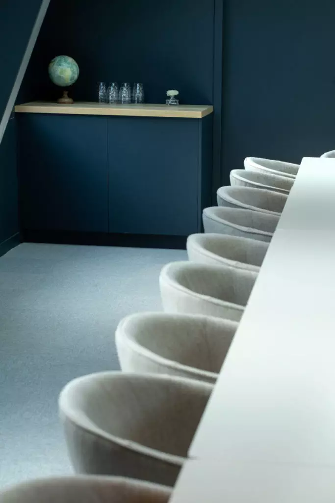 Chaises grises alignées dans salle de réunion épurée, globe et verrerie au fond, lieu séminaire team building Dijon.