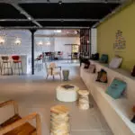 Intérieur café Salt & Pepper Dijon avec estrades, coussins colorés, chaises bois et espace atelier culinaire chaleureux.
