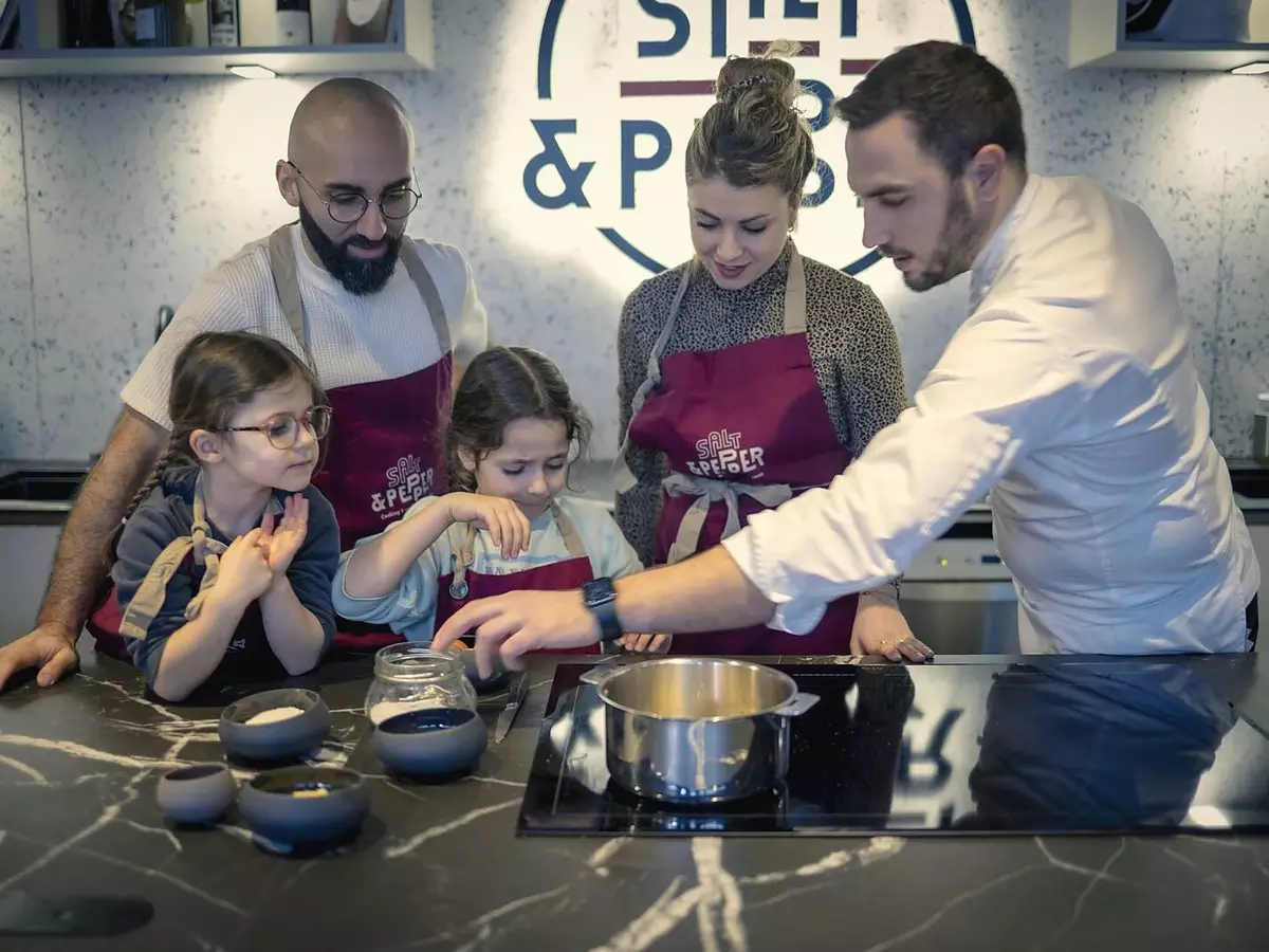 Une famille en cours de cuisine avec un chef au Cooking Lab de Salt & Pepper à Dijon