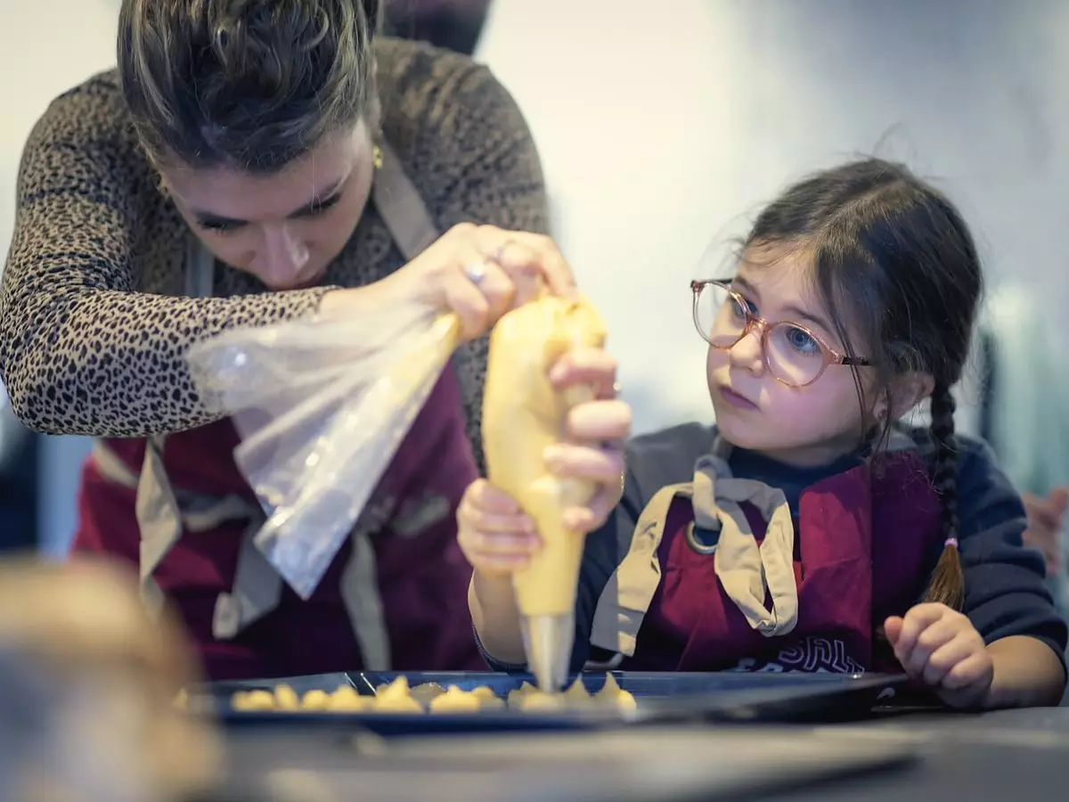 Une enfant apprend la poche à douille avec sa maman en cours de pâtisserie à Dijon