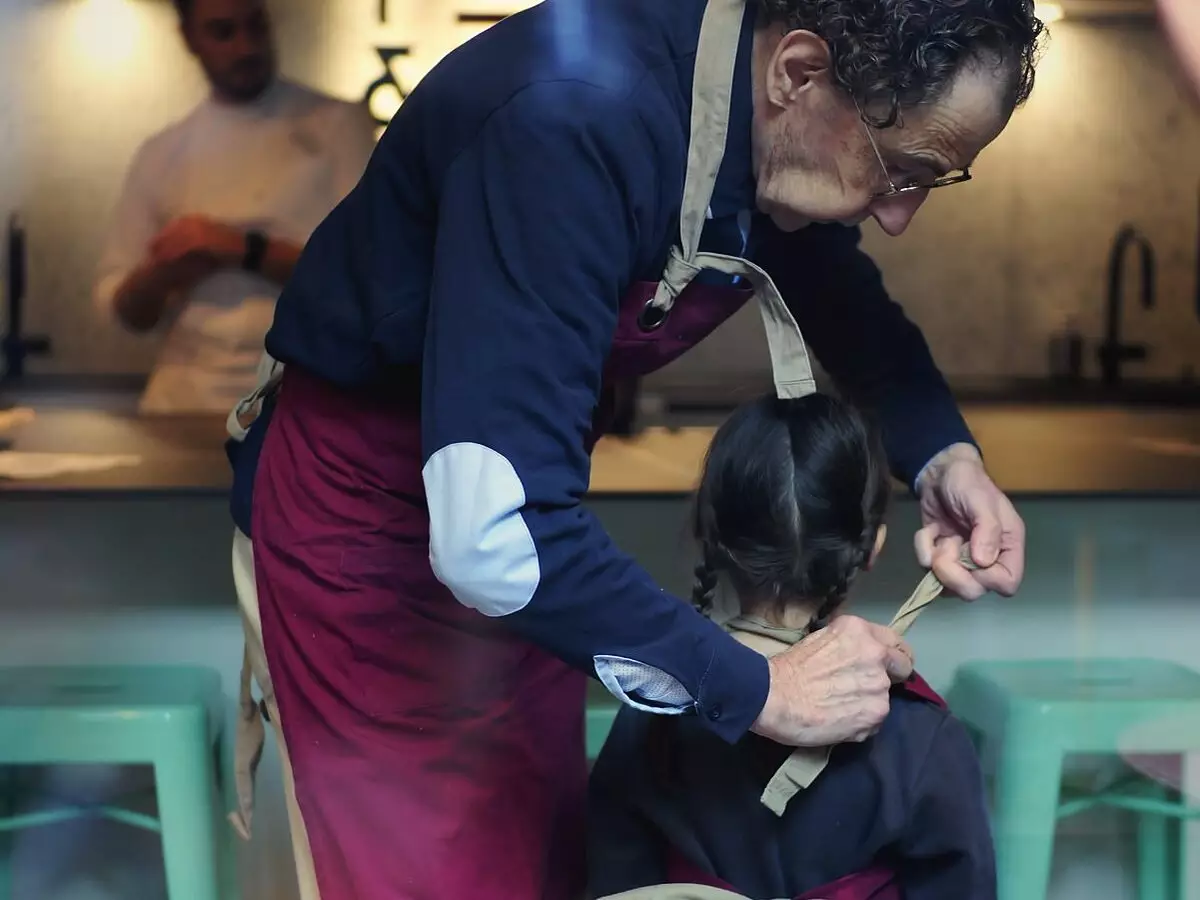 Un chef noue le tablier d'un enfant avant un cours de cuisine à Dijon